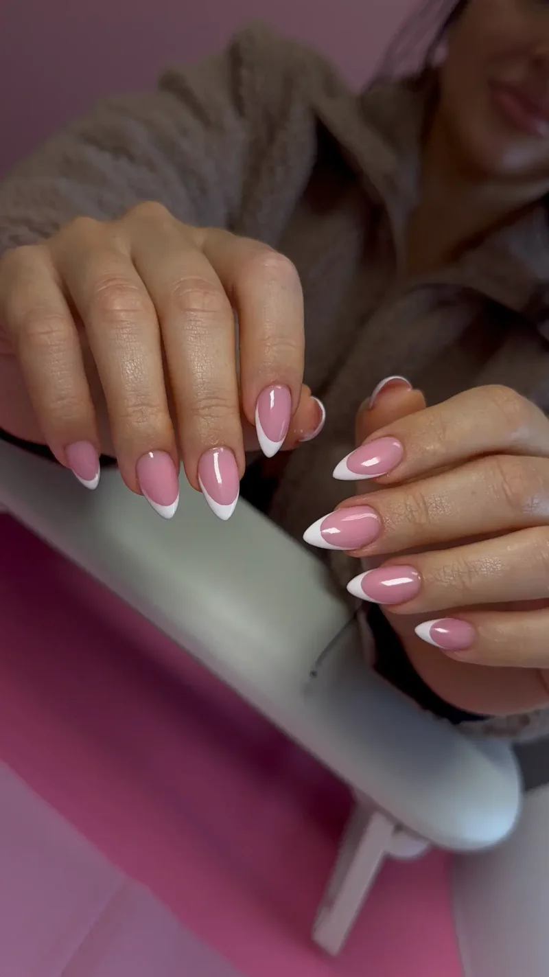 Classic white french tip nails on medium almond shape with sheer pink base